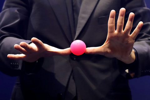 Norbert Ferré holding a pink ball between his thumbs, with his fingers spread.