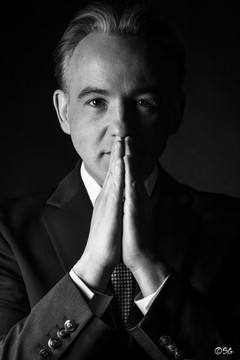 Black and white portrait of Norbert Ferré with his hands together.