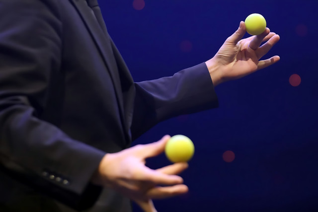 Norbert Ferré performing sleight of hand with two yellow balls.